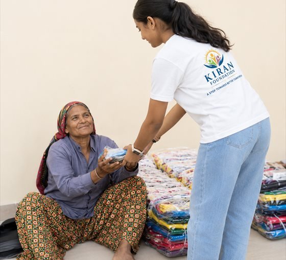 A Kiran Foundation volunteer handing out clothing to a woman