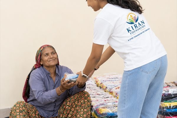 A volunteer handing out clothing to a woman